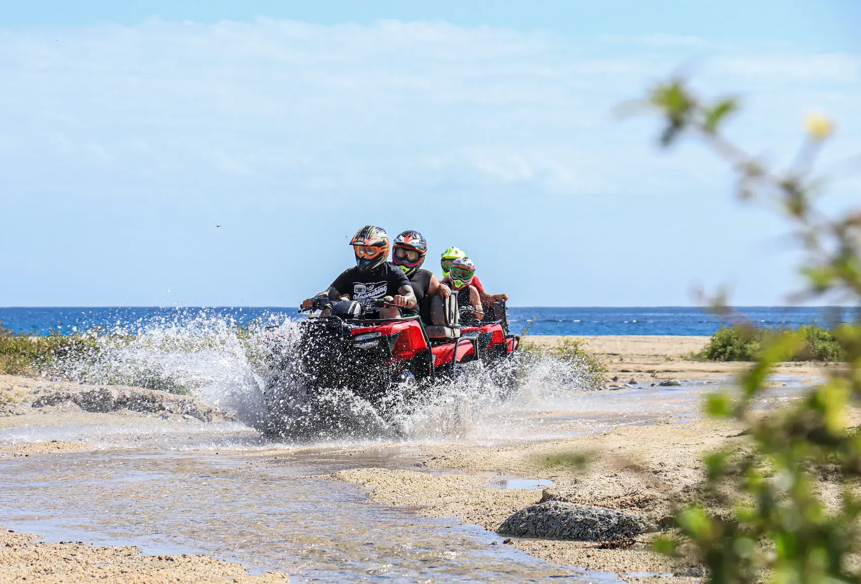 Familia en ATV cruzando el agua en la playa
