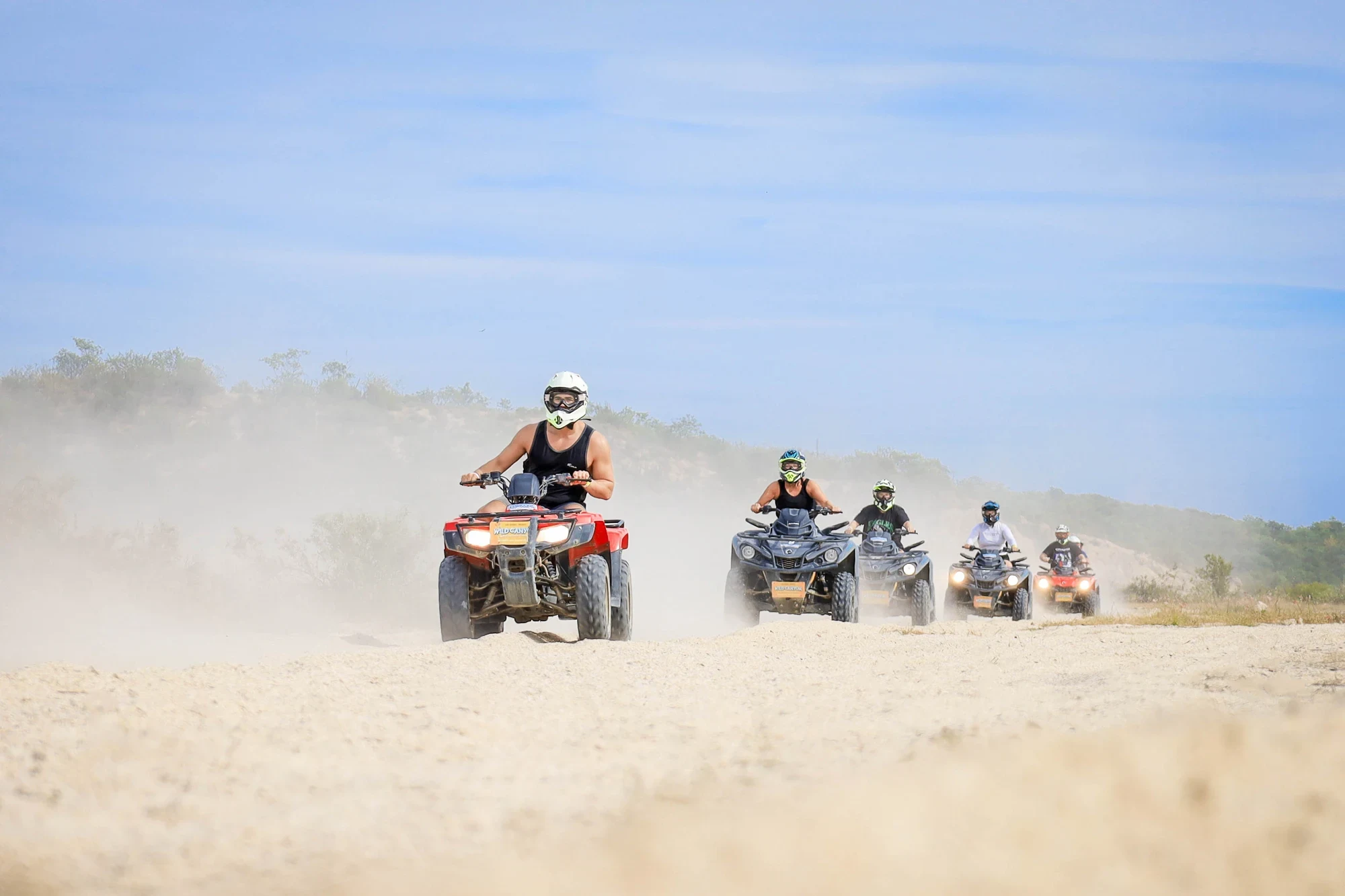 Convoy de cinco ATV levantando polvo entre las dunas del desierto