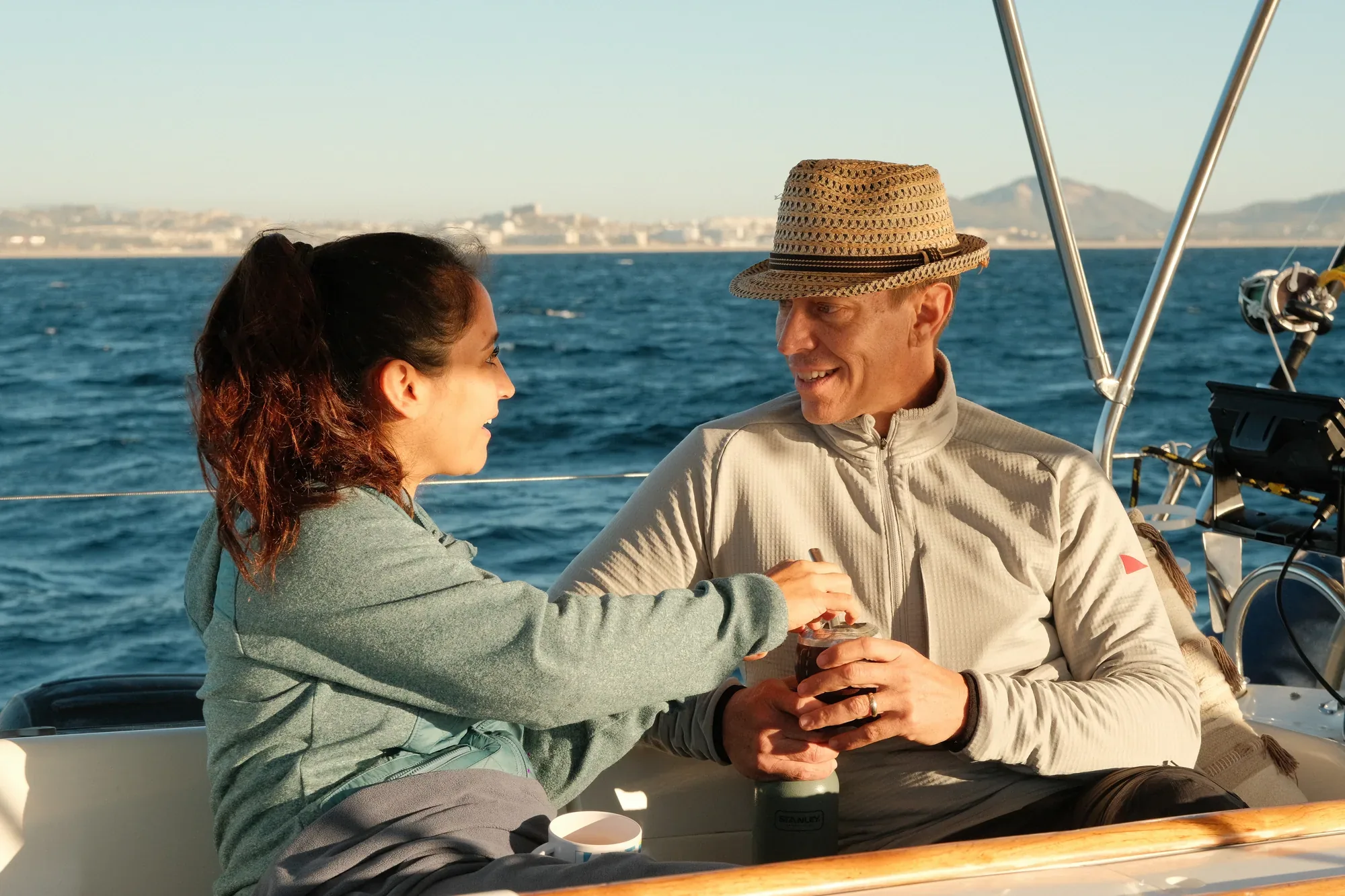 Pareja brindando con bebidas de la barra libre en la cubierta del velero Aura