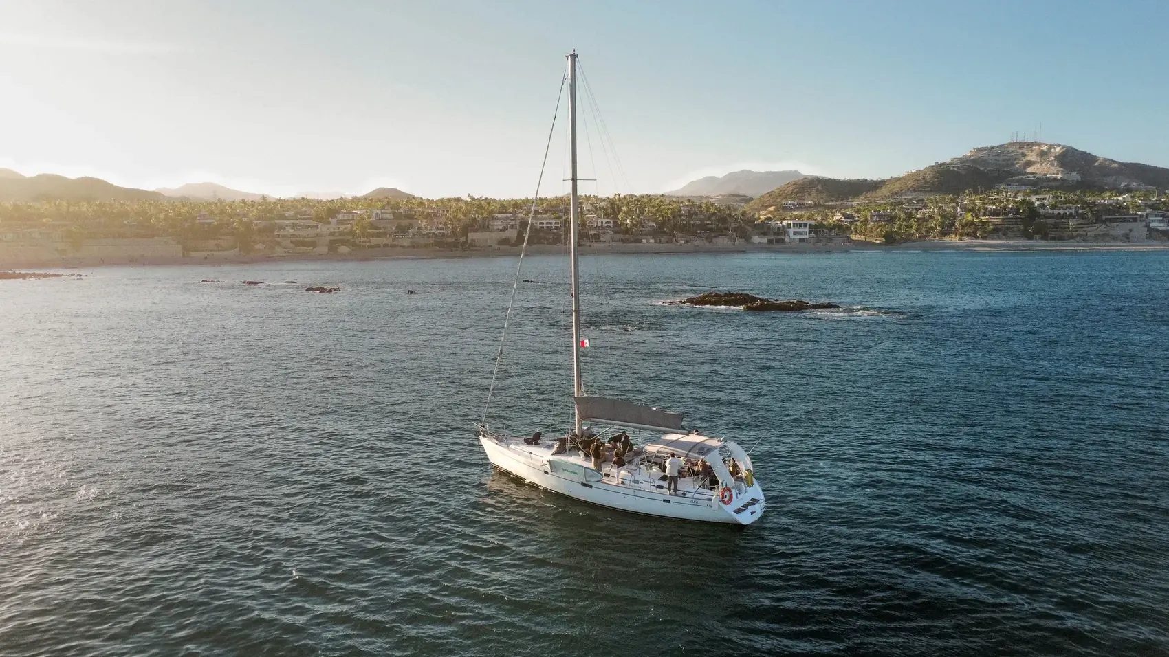 Velero Aura navegando al atardecer frente a la costa de San José del Cabo