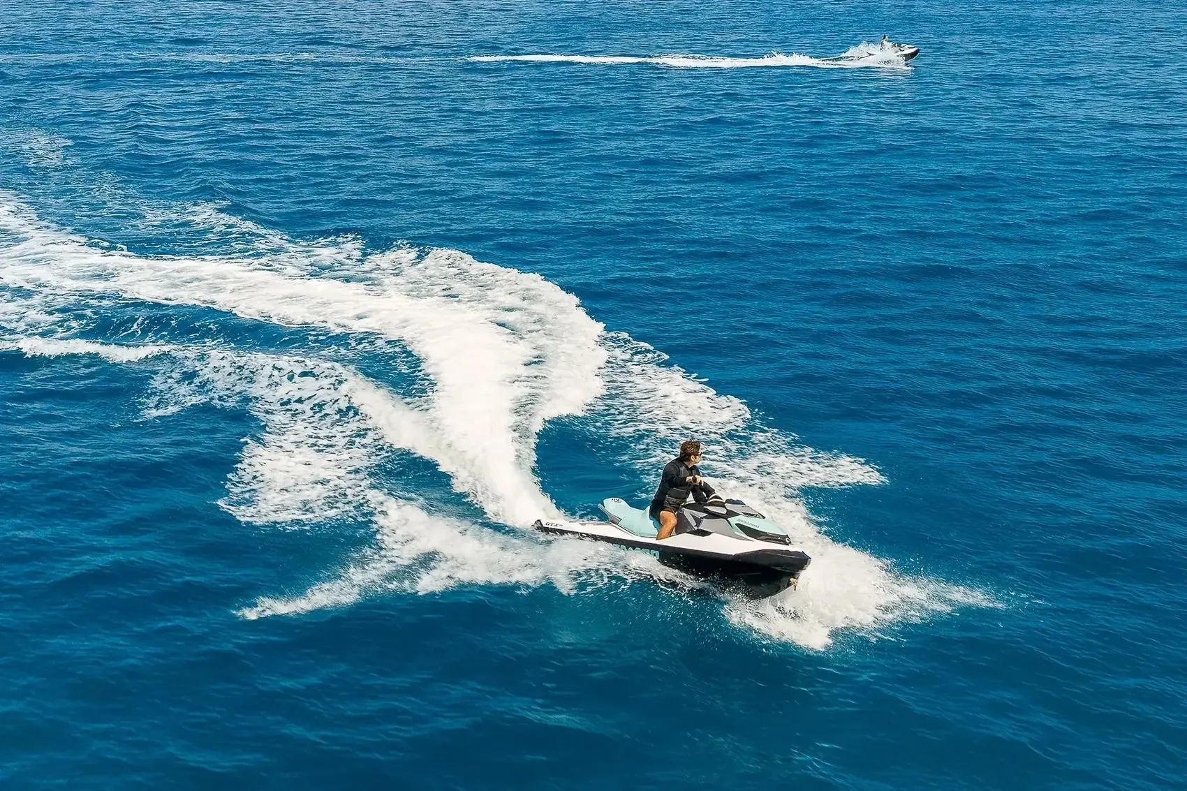 Vista aerea de un Sea-Doo trazando su estela sobre el mar azul abierto