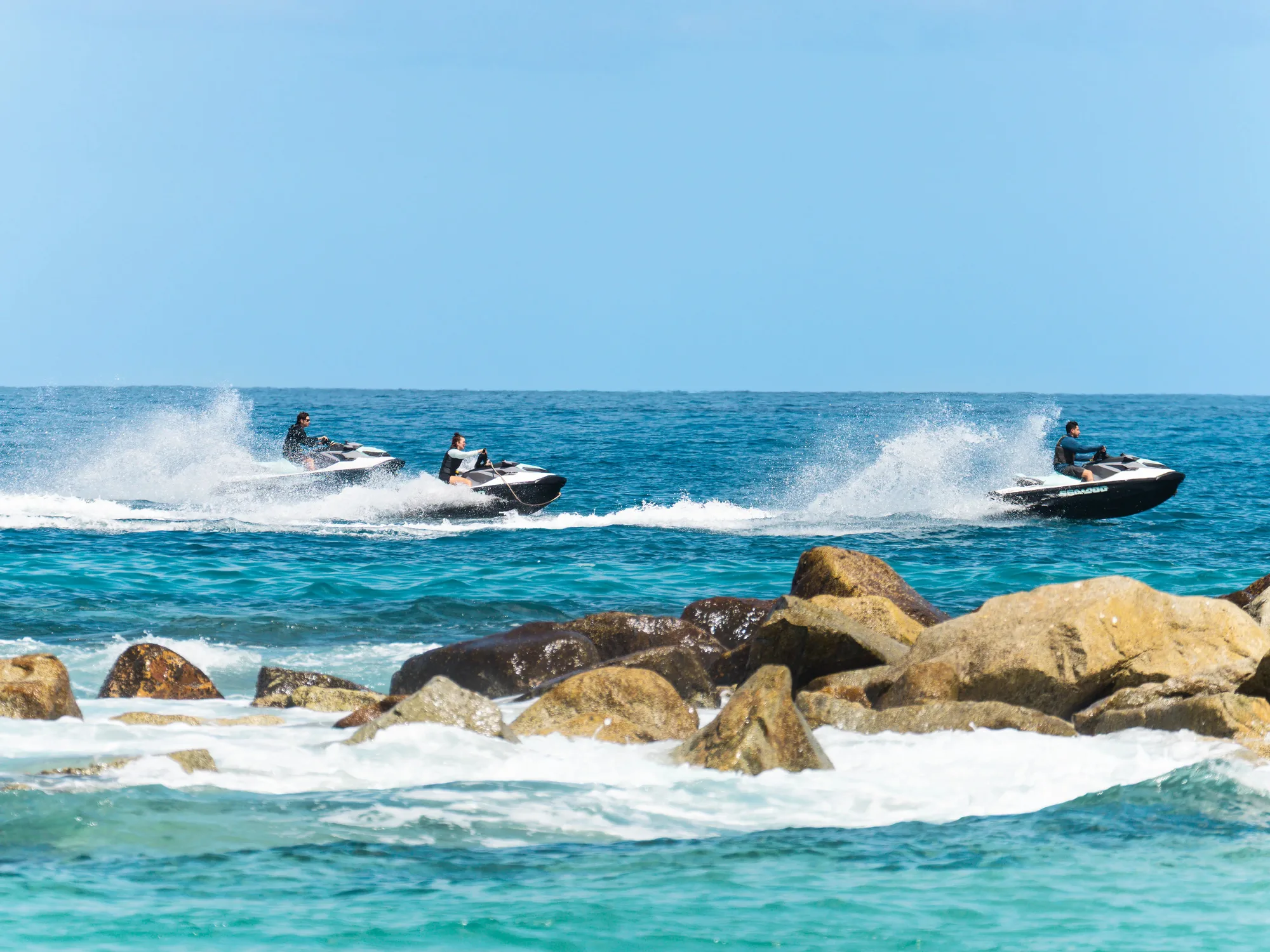 Tres Sea-Doo recorriendo la costa rocosa de Los Cabos con oleaje