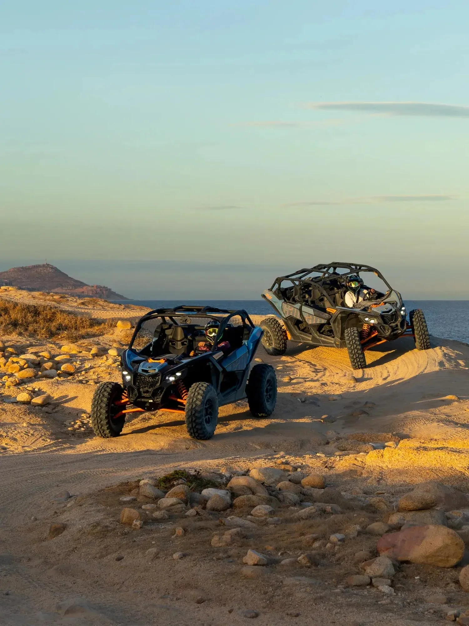 Dos Can-Am UTV en un acantilado costero con vista al oceano al atardecer