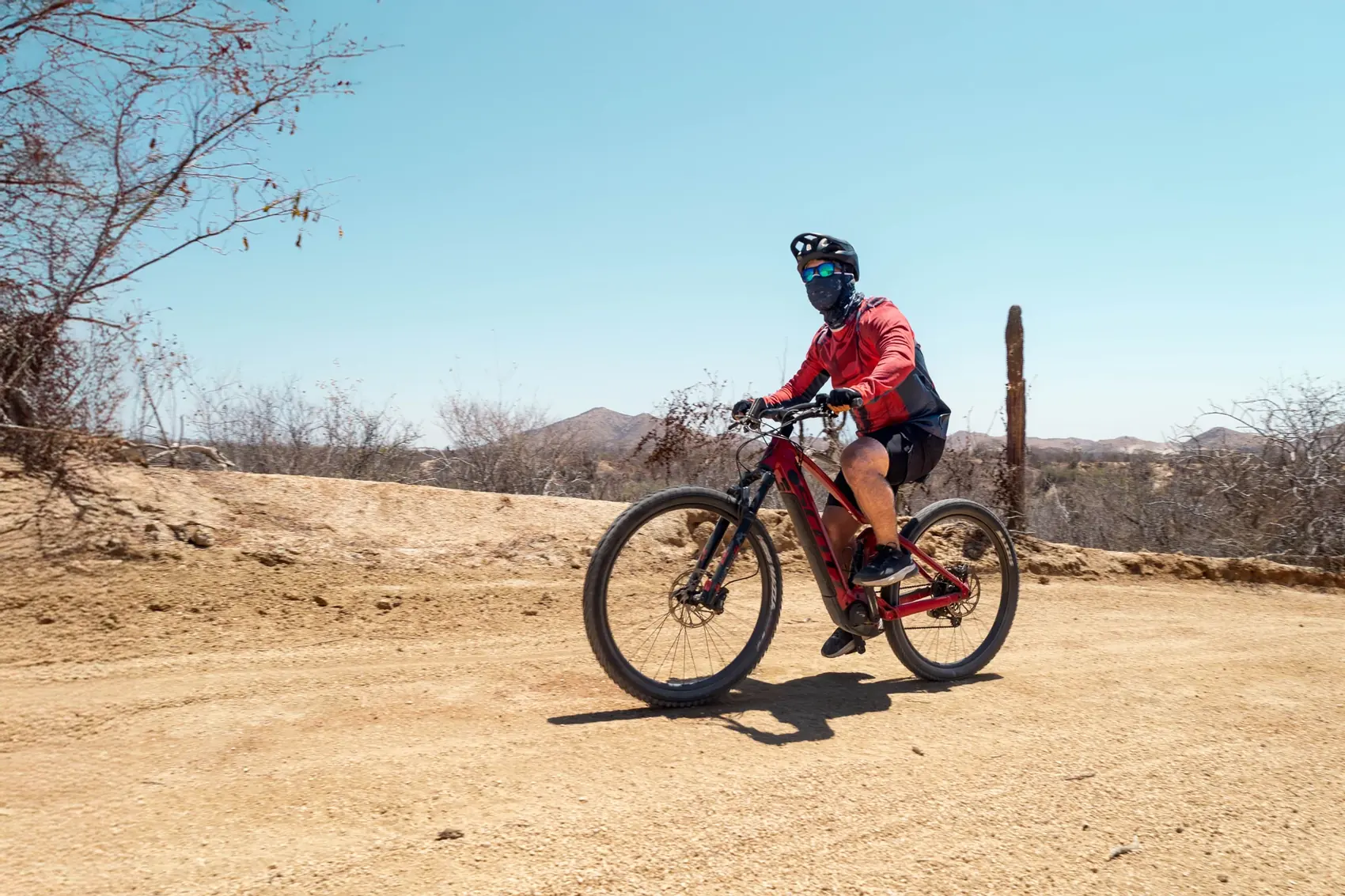 Rider solitario en sendero de tierra con montanas de fondo