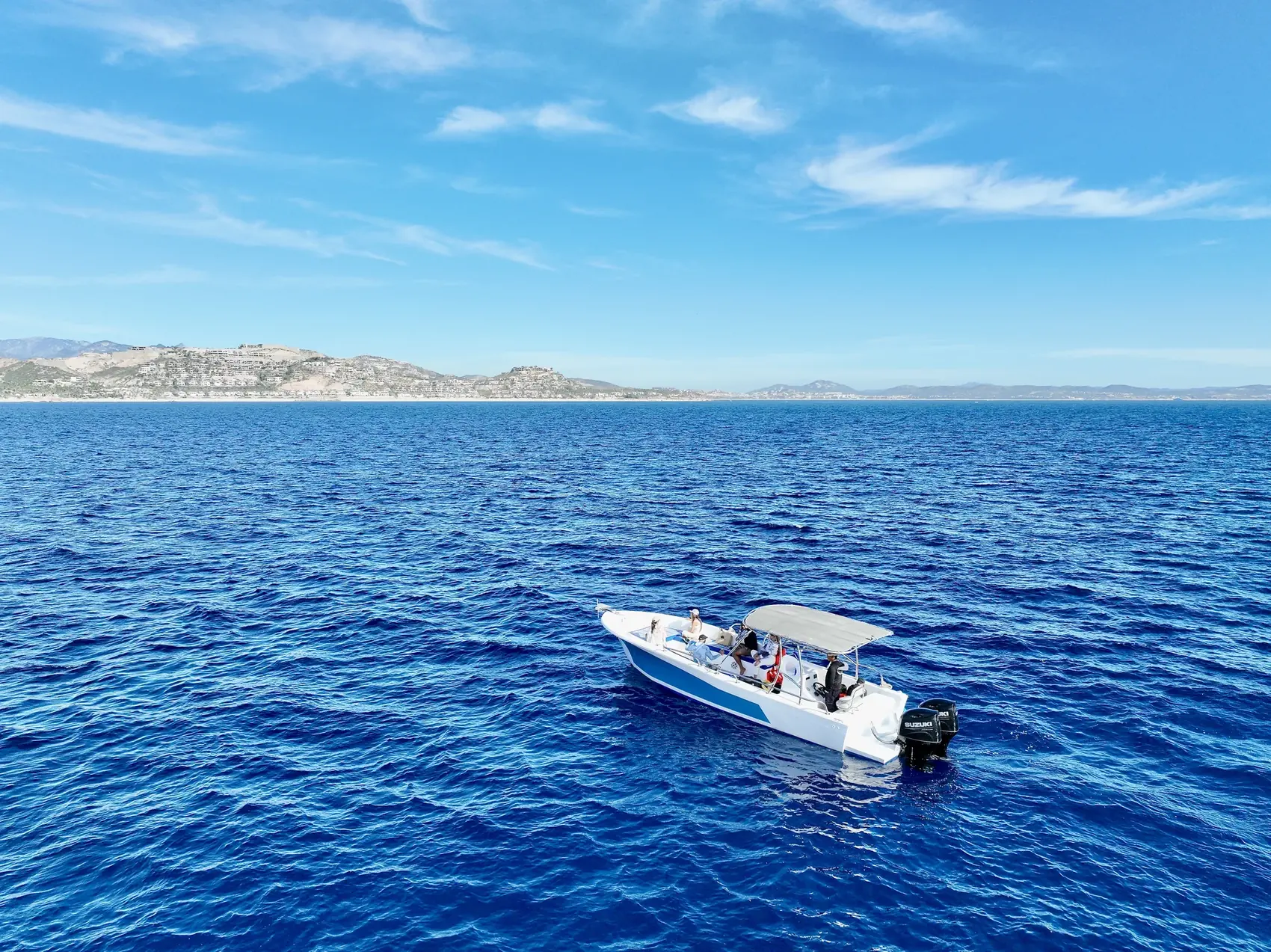 Barco de expedición con franja azul sobre el Mar de Cortés frente a San José del Cabo
