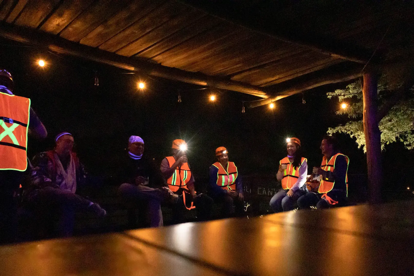 Grupo sentado de noche bajo luces con bebidas en mano