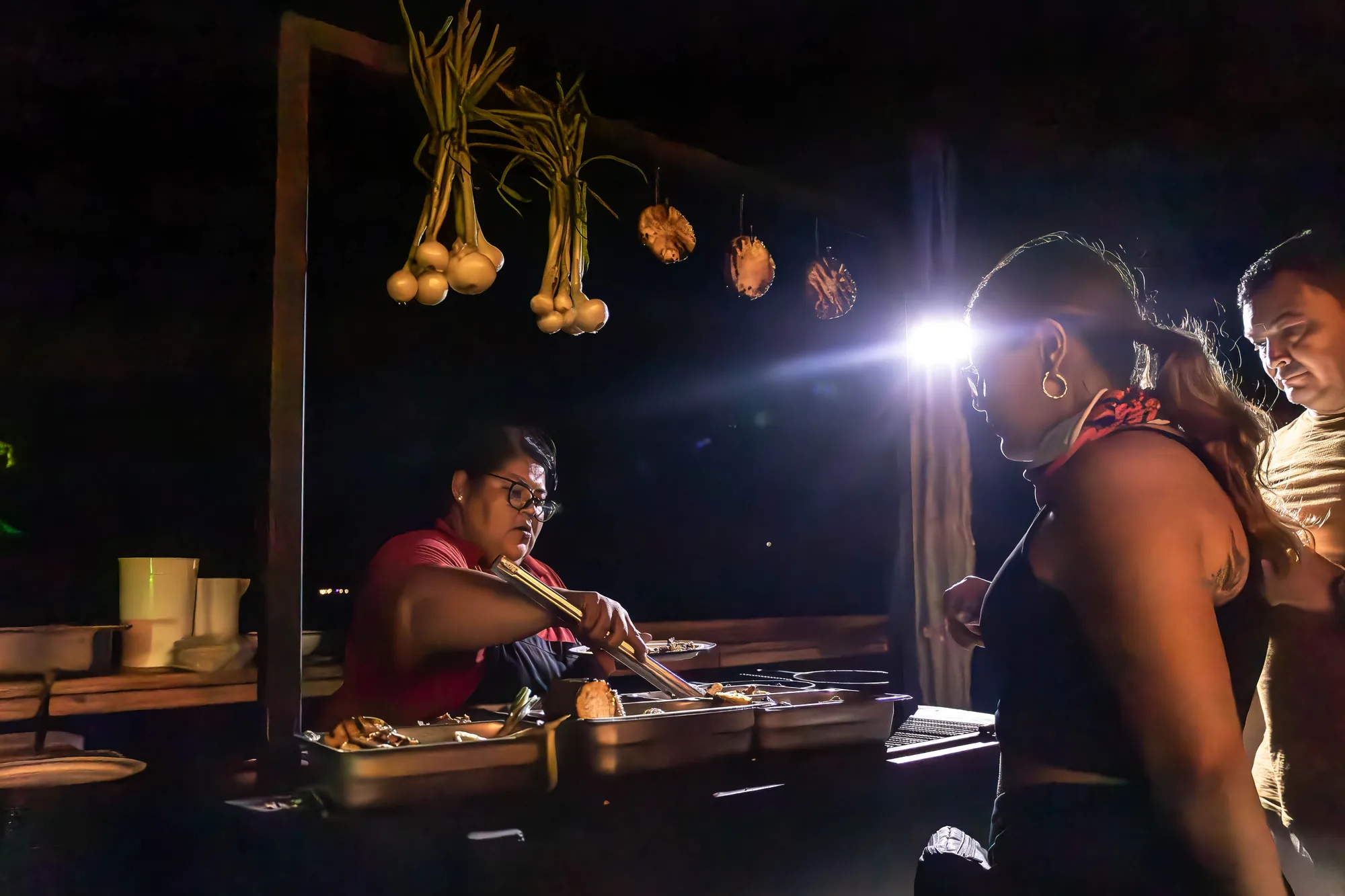 Personal sirviendo comida de noche iluminado por lampara frontal
