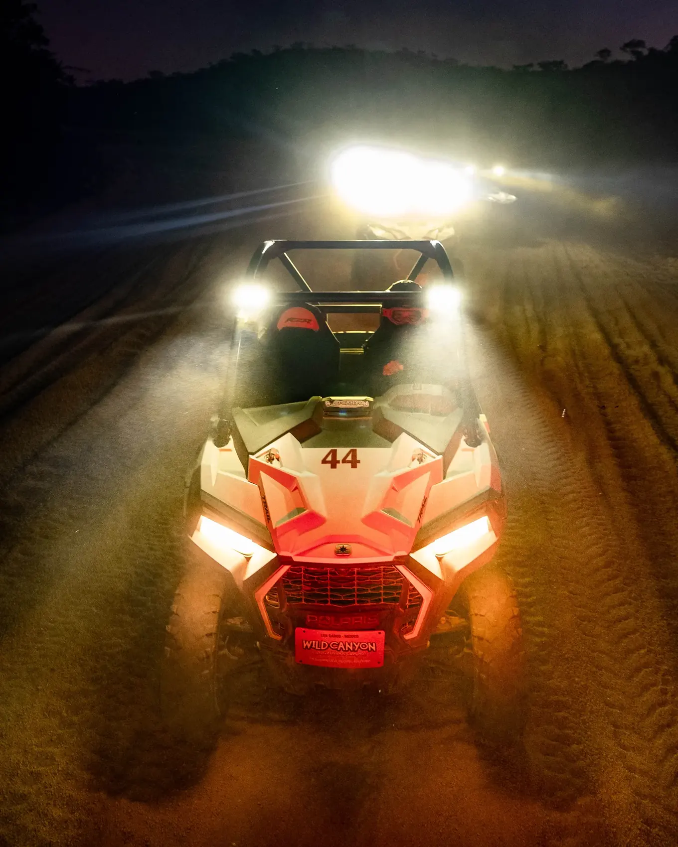 UTV con faros encendidos atravesando la oscuridad total del desierto