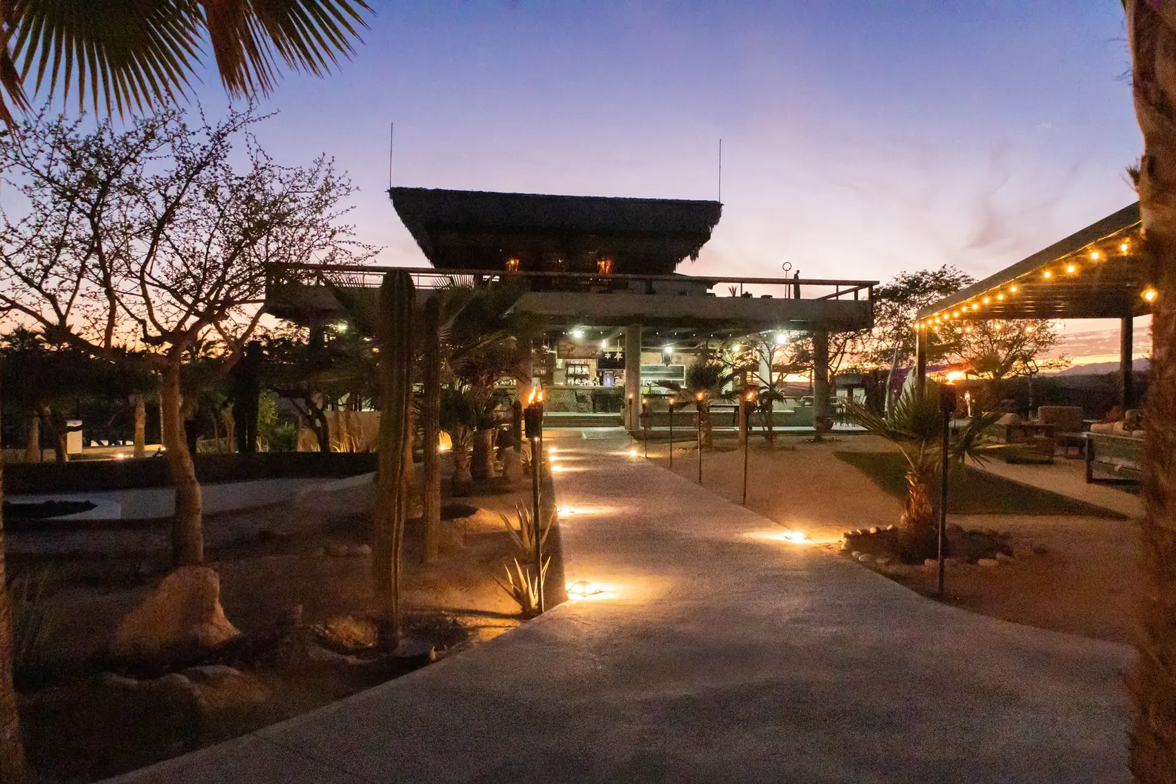 Palapa del restaurante al atardecer bordeada de antorchas