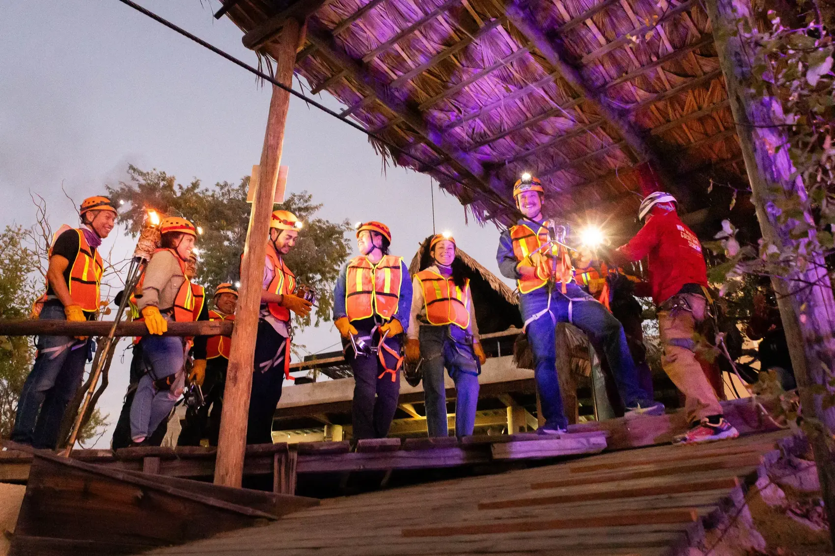 Grupo en la plataforma de tirolesa iluminada de morado con antorcha