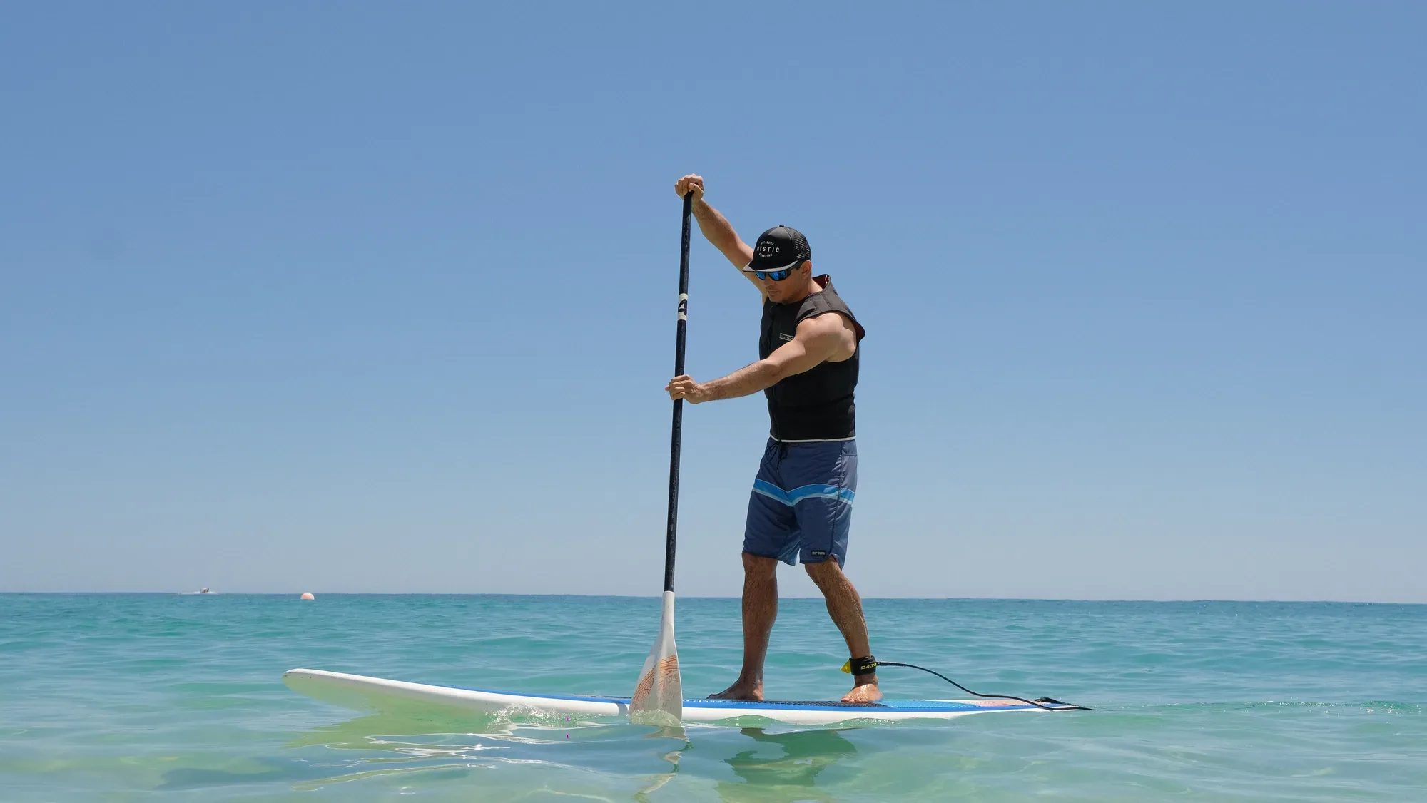 Hombre remando en stand-up paddle sobre agua turquesa en Wild Bay