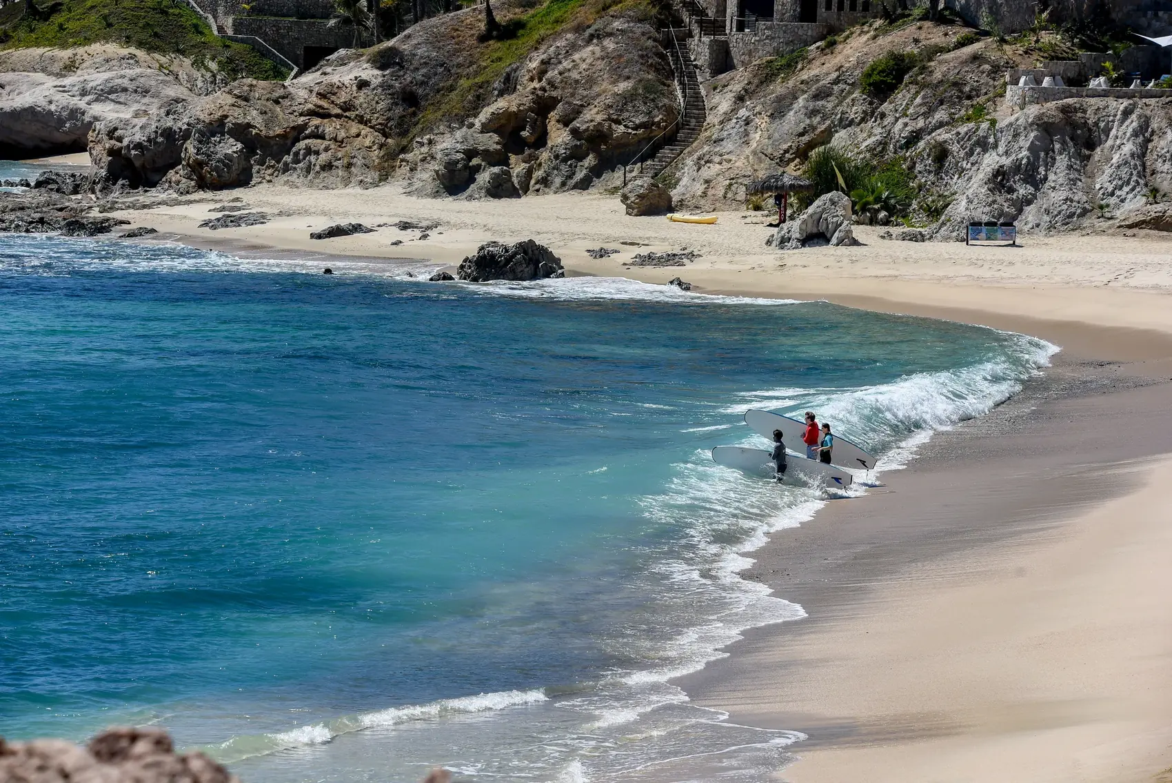 Cala de Playa Acapulquito con surfistas entrando al agua con sus tablas