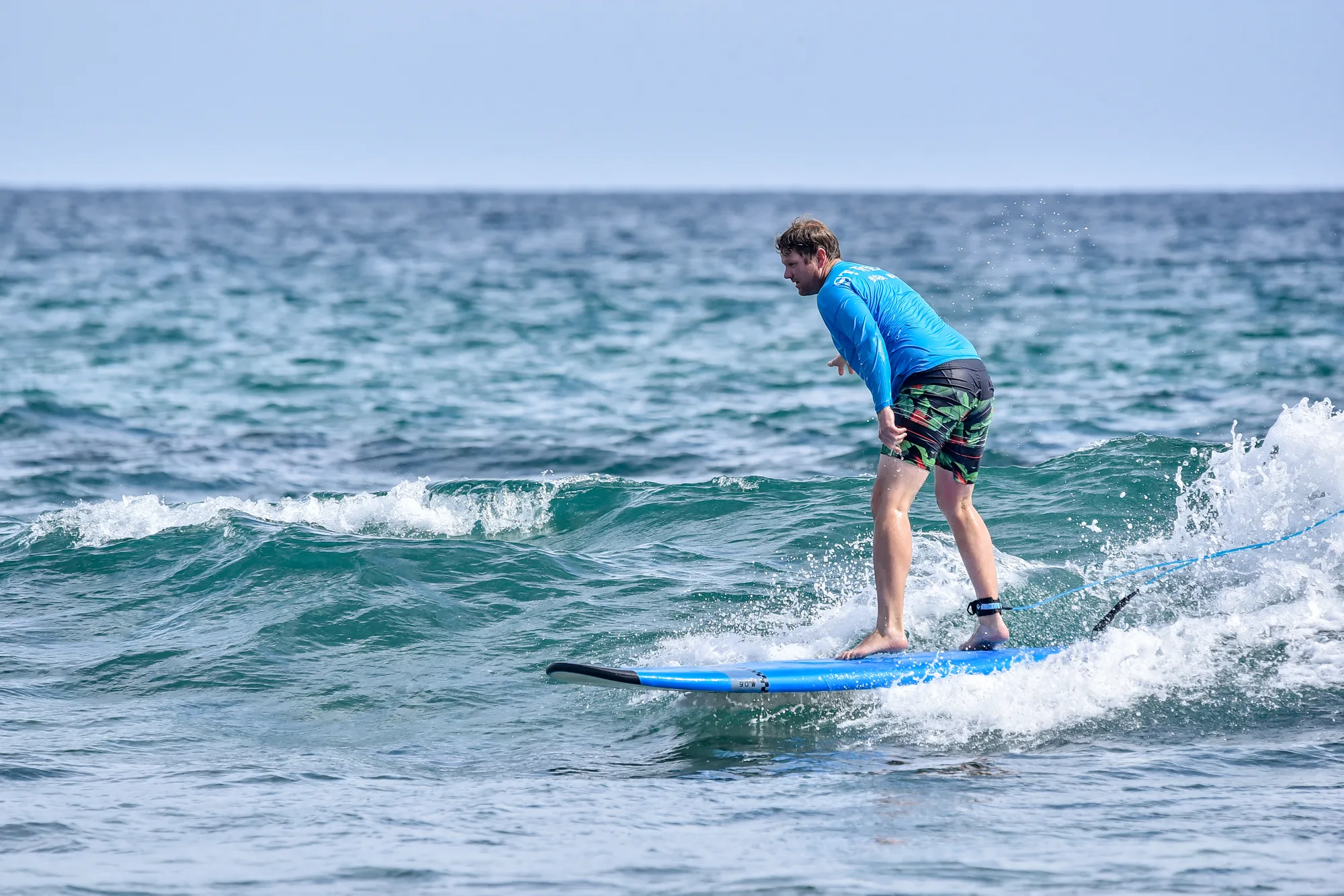 Hombre surfeando una ola en tabla azul en Acapulquito